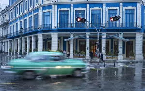 Cuba Gallery: Cuba, Havana. A classic car passes by in a rainstorm the city