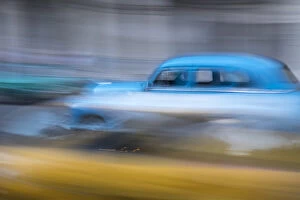 Cuba Gallery: Cuba, Havana. Classic cars speed by in a blur along the streets of the city