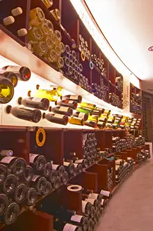 A curved display of bottles. Backlit The Lavinia wine shop in Paris. Probably