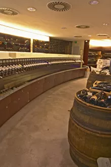 A curved display of bottles and a barrel used to present bottles The Lavinia wine shop in Paris