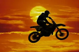 Safety Prints: Digital composite of motocross racer doing jump in front of big sun
