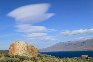 Dramatic clouds in the blue sky over meadow and Lago Pehoe, Torres del Paine National Park