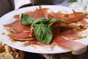 Dried dry cured ham with basil leaves on a white plate. Tradita traditional restaurant, Shkodra