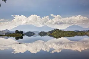 Paddle Prints: Dugout canoe floating on Lake Mutanda with the Virunga Vulcanoes in the background