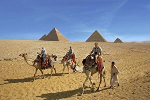 Egypt, Cairo, Giza, Tourists ride with a guide in front of the great pyramids