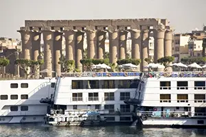 Egypt, Luxor. Nile cruise boats docked side by side and the gigantic columns of Luxor