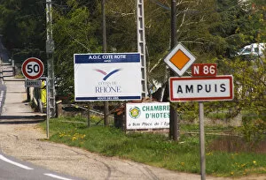 The entrance to Ampuis with road signs with the name of the town and a big sign saying