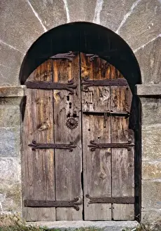 Europe, Andorra. An ancient old wooden door contrasts against a stone building in Andorra
