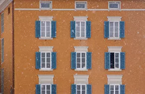 Images Dated 27th November 2005: Europe, Austria, Salzburg. Blue shutters on orange apartment building in snowfall