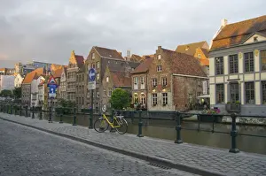 Flanders Prints: Europe, Belgium, Ghent. A bicycle parked on a paved-stone sidewalk by the water