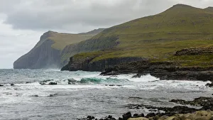 Europe, Faroe Islands. View of the northern coast pounded by storm surf from the village