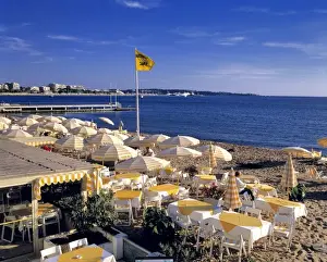 Europe, France, Cannes. The yellow stripped umbrellas on the beach at Cannes awaits