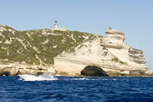 France Collection: Europe, France, Corsica, Bonifacio. Boat passes Capo Pertusato lighthouse