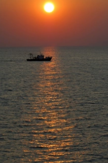 Europe, Greece, Crete (aka Kriti). Aegean sunset with Greek fishing boat