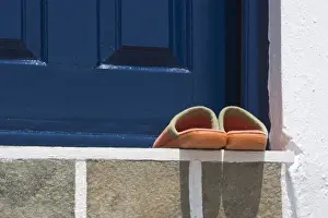 Europe, Greece, Mykonos, Hora. Orange slippers on threshold of blue door. Credit as