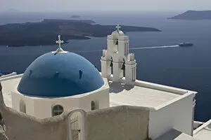 Europe, Greece, Santorini. Greek Orthodox church and white bell tower overlook a luxury yacht