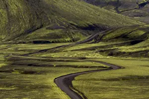 Images Dated 24th July 2012: Europe, Iceland. Black dirt road curves through green countryside