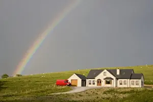 Donegal Prints: Europe, Ireland, Donegal. Afternoon rainbow arcs across the sky over a house in