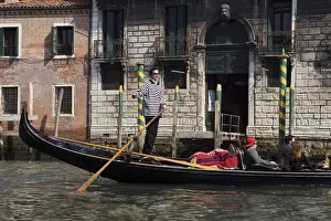 Images Dated 12th February 2009: Europe, Italy, Venice. A gondolier strikes a pose on his gondola