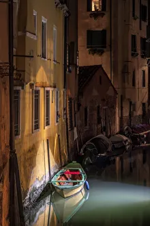Still Prints: Europe, Italy, Venice. Wooden boat and reflections on still canal at night