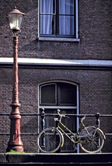 North Holland Prints: Europe, Netherlands, Amsterdam. Near a striking red lampost, a bicycle waits for its rider