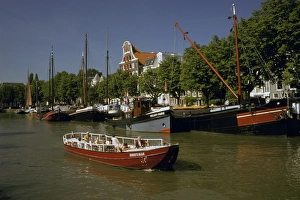 Boating Prints: Europe, Netherlands, Dordrecht. Boats lining canal, with tourist boat motoring by