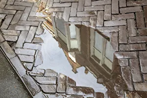 Netherlands Prints: Europe, Netherlands, The Hague. Buildings reflected in sidewalk rain puddle