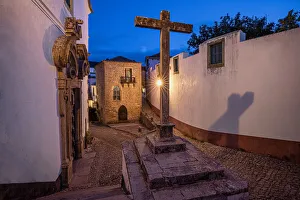 Cobbled Prints: Europe, Portugal, Obidos. Church and cross on cobblestone street at sunset