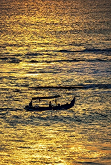 Bali Prints: Fishing boat returning to shore in a blaze of gold sunset light in Bali, Indonesia