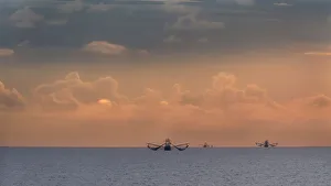 Sheila Haddad Prints: Fishing boats deep out to sea against the backdrop of dramatic sunset clouds and sky