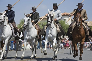 Images Dated 14th July 2007: France, Camargue, Saintes-Maries-de-la-Mer. Horseman and horses ride down the main