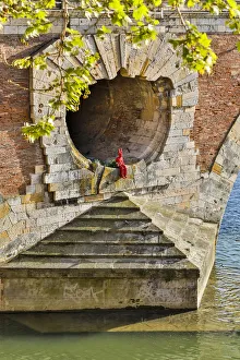 France, Toulouse. Red Devil sitting in opening of the Pont Neuf (Bridge)