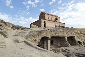 Images Dated 22nd September 2014: Georgia, Uplistsikhe. A room carved into a cliff face, with a church in the background
