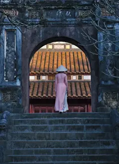 Girl in Ao Dai (traditional Vietnamese long dress) and conical hat at Minh Mang Tomb