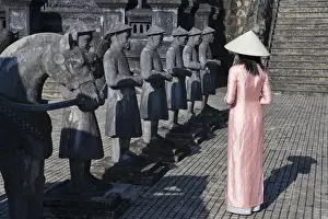 Girl in Ao Dai (traditional Vietnamese long dress) and conical hat at Tomb of King