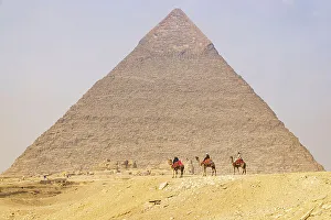 Cairo Prints: Giza, Cairo, Egypt. Men on camels at the Great Pyramid complex. (Editorial Use Only)