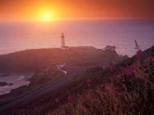 A golden glow sets over Yaquina Head Lighthouse as the sun sets over the ocean, Oregon