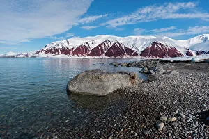 Gravel Prints: A gravel shoreline and snow covered mountains border Bockfjorden