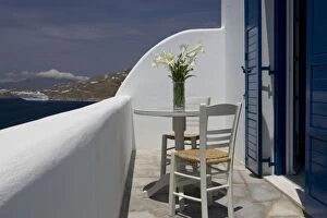 Greece, Mykonos, Hora. Balcony table and chairs with a docked cruise ship in the distance