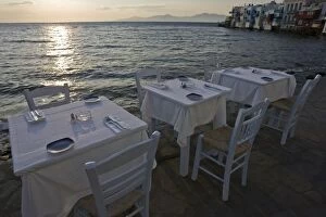 Greece, Mykonos, Hora. Three dinner tables overlooking the sea at sunset. Credit as