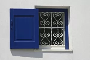 Greece, Mykonos, Hora. Open window with blue shutter and iron grill contrast with white wall