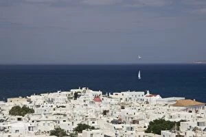 Greece, Mykonos, Hora. Overlook of town of and sailboat on ocean