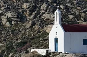 Greece, Mykonos. Sunlit face of church with rocky hill in background