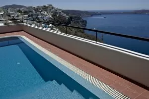 Greece, Santorini. Swimming pool overlooking town of Firostefani and yachts on the Aegean Sea