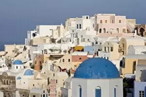 Greece, Santorini, Thira, Oia. Blue dome of Greek Orthodox church with town in the background