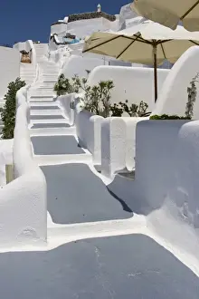 Stair Case Prints: Greece, Santorini, Thira, Oia. Grey and white painted stairs leading past open patio umbrellas
