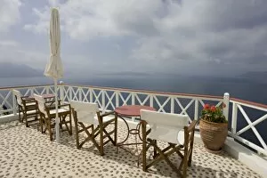 Images Dated 7th June 2005: Greece, Santorini, Thira, Oia. Patio tables and chairs on pebbled deck overlooking misty sea