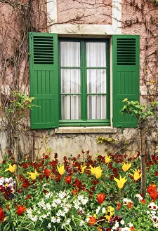 Green shutters at a window overlooking a garden in France