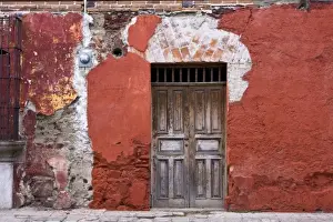 Guatemala, Antigua. An old wooden door and colorful wall along the streets of Antigua