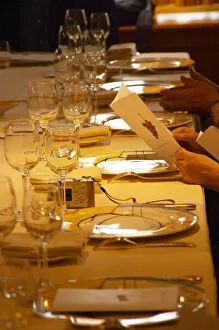 A guest holding up and reading the menu in anticipation of the meal. In the restaurant